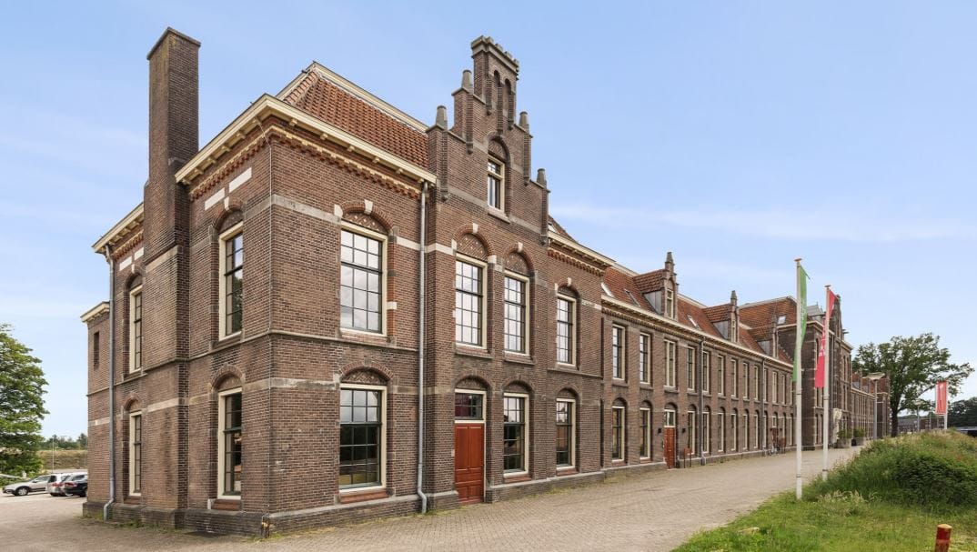 Monumentaal bakstenen gebouw met hoge ramen op het World Food Center-terrein in Ede
